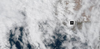 NOAA Weather Satellite image showing cloud cover over a coastal region and adjacent ocean, with dashed border lines and a small black location marker.