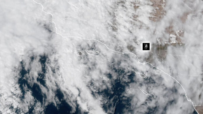 NOAA Weather Satellite image showing cloud cover over a coastal region and adjacent ocean, with dashed border lines and a small black location marker.