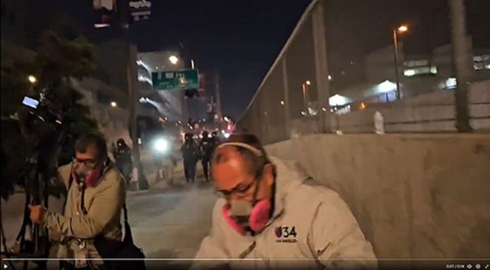 Screenshot of video provided by Lexis-Olivier Ray | A TV news crew from Univision runs from an advancing line of federal officers shooting pepper balls at protestors and press