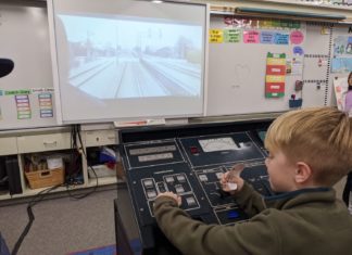 Arroyo Vista Elementary South Pasadena: AV STEM Night 2025 A young student sits at a Metro train control training board with a simulated view of the 'A line'