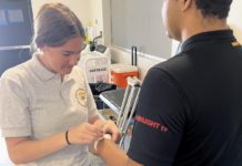 PHOTO: SPHS sports medicine student Keira Adams helps prepare football player Guillermo Melara for practice. (Photo Courtesy of Andre Zumaeta)