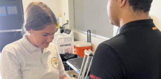 PHOTO: SPHS sports medicine student Keira Adams helps prepare football player Guillermo Melara for practice. (Photo Courtesy of Andre Zumaeta)