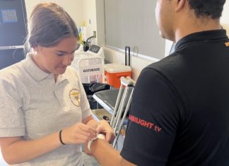 PHOTO: SPHS sports medicine student Keira Adams helps prepare football player Guillermo Melara for practice. (Photo Courtesy of Andre Zumaeta)