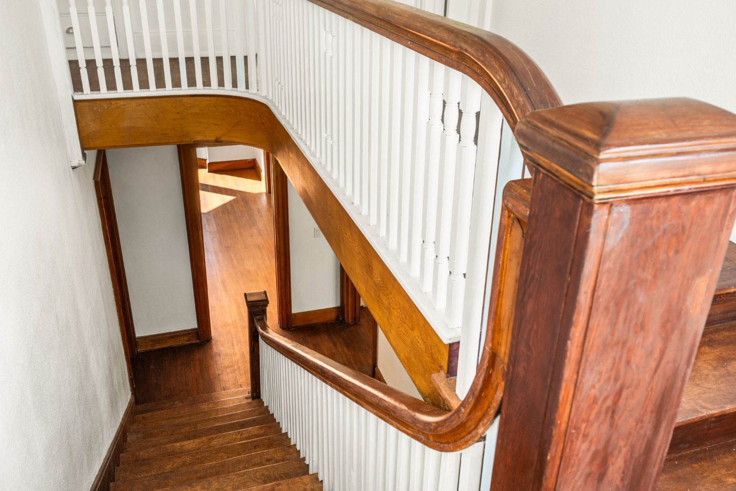 | The South Pasadenan | South Pasadena News Curved wooden staircase with white balusters and a polished handrail, viewed from the upper landing