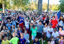Soccer Watch Party at Garfield Park Monday July 6 – South Pasadena to Host 2nd Event South Pasadena World Cup in Garfield Park crowd at a park celebration, many people raising hands and smiling, with an American flag visible in the background.