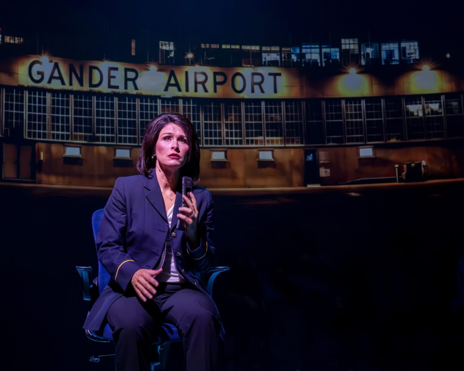 | The South Pasadenan | South Pasadena News Woman in a navy suit seated on a stage, holding a microphone, with a lit'GANDER AIRPORT' sign in the background.