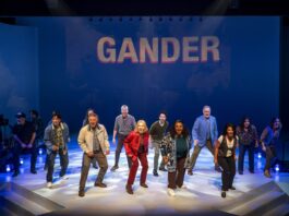 COME FROM AWAY soars on joy, hope and the kindness of strangers at A Noise Within Diverse cast dancing on a stage beneath a blue backdrop that reads GANDER.