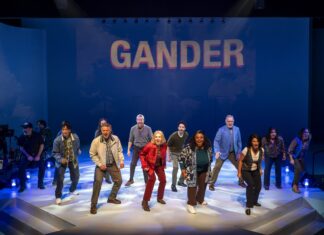 Diverse cast dancing on a stage beneath a blue backdrop that reads GANDER.