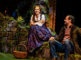 Betsy Morgan as Fiona and Max von Essen as Tommy in Brigadoon at Pasadena Playhouse. A Couple sits on a green hillside in the Scottish highlands. The man looks lovingly at the woman.