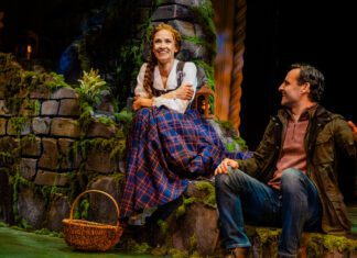 Betsy Morgan as Fiona and Max von Essen as Tommy in Brigadoon at Pasadena Playhouse. A Couple sits on a green hillside in the Scottish highlands. The man looks lovingly at the woman.