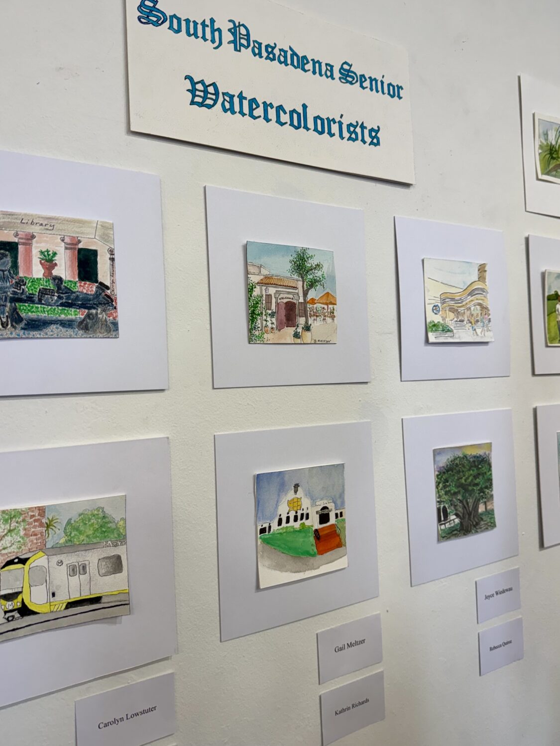 south-pasadena-news-07-12-2026-the-creative-life-blooms-senior-watercolorists 1 | The South Pasadenan | South Pasadena News Wall display of small watercolor paintings mounted on light gray mats, labeled'South Pagadena Senior Watercolists'
