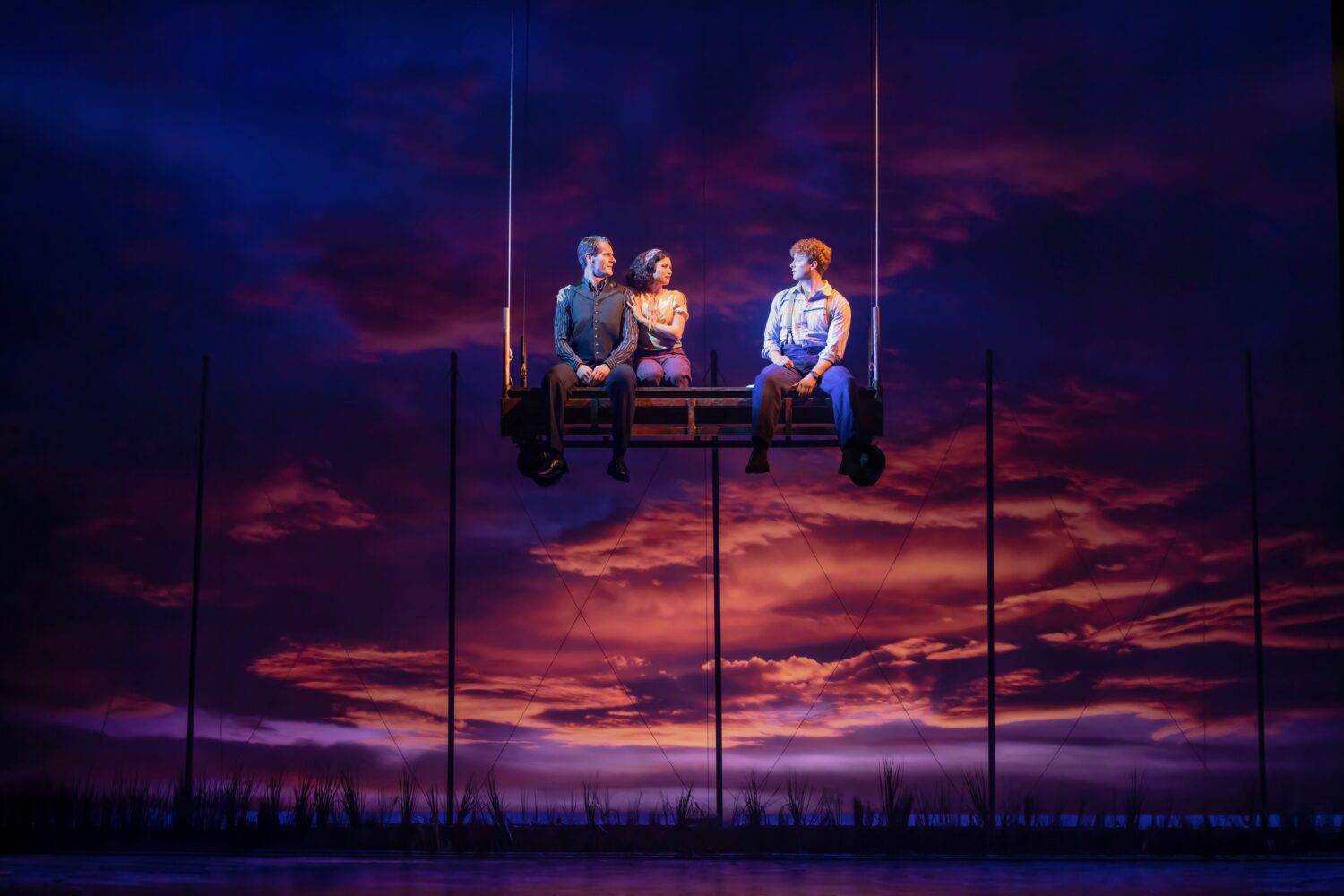 | The South Pasadenan | South Pasadena News Three adults share a suspended bench ride against a dramatic orange-pink sunset sky, silhouetted poles in the background.