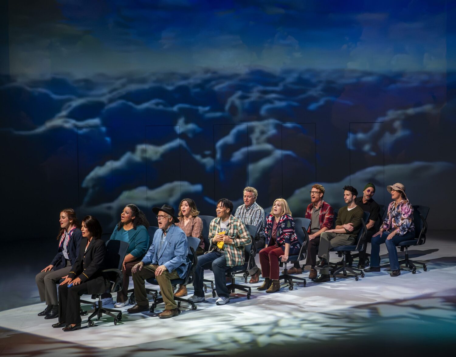 | The South Pasadenan | South Pasadena News Group of diverse people seated in a row of office chairs on a stage, singing, with a blue cloudy backdrop behind them.