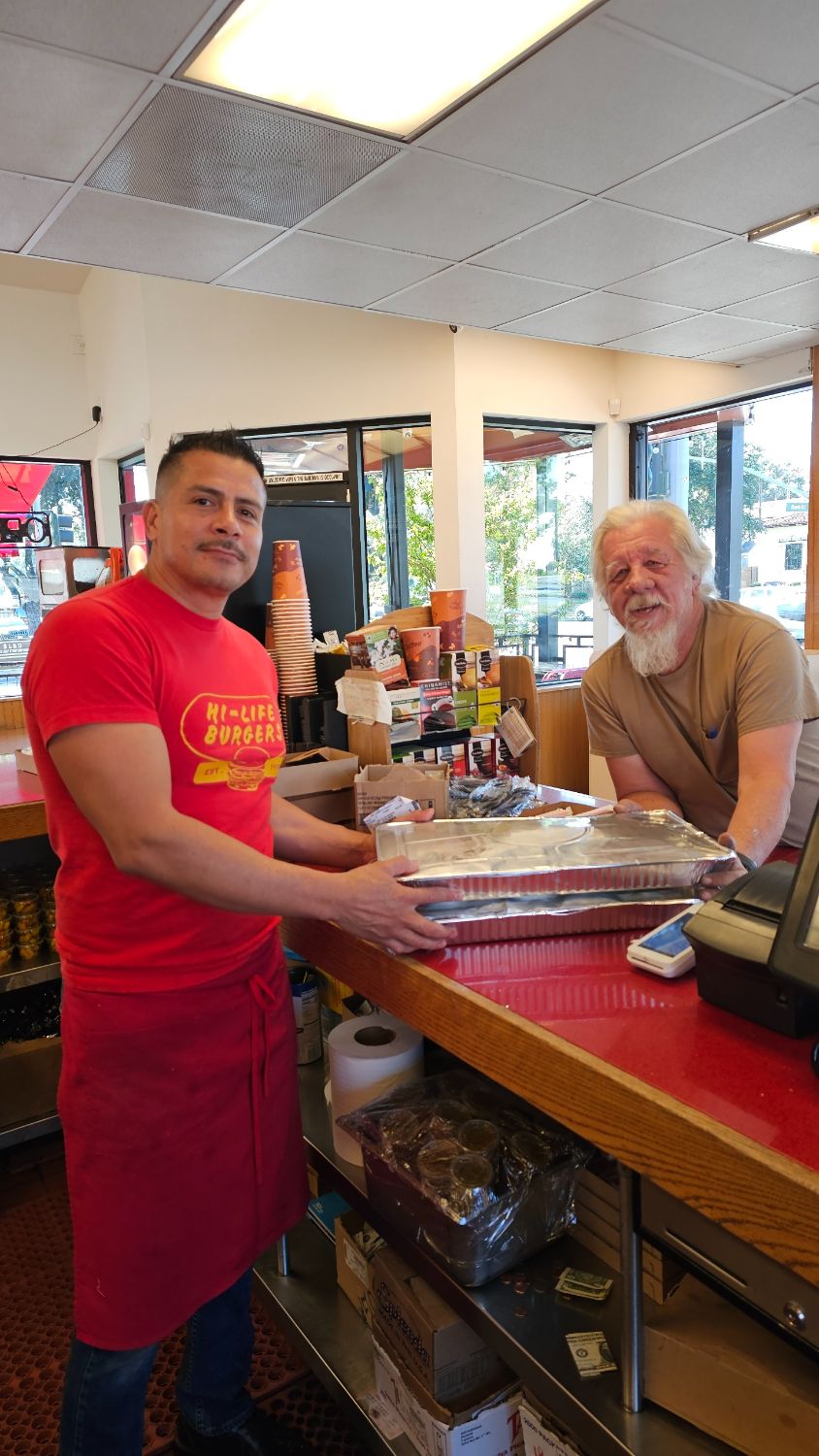 PHOTO: South Pasadena Tournament of Roses | The South Pasadenan | Float construction crew member Steve Fillingham (right) picks up the lunch order from Hi-Life Burgers’ Manager Rodrigo Cisneros.
